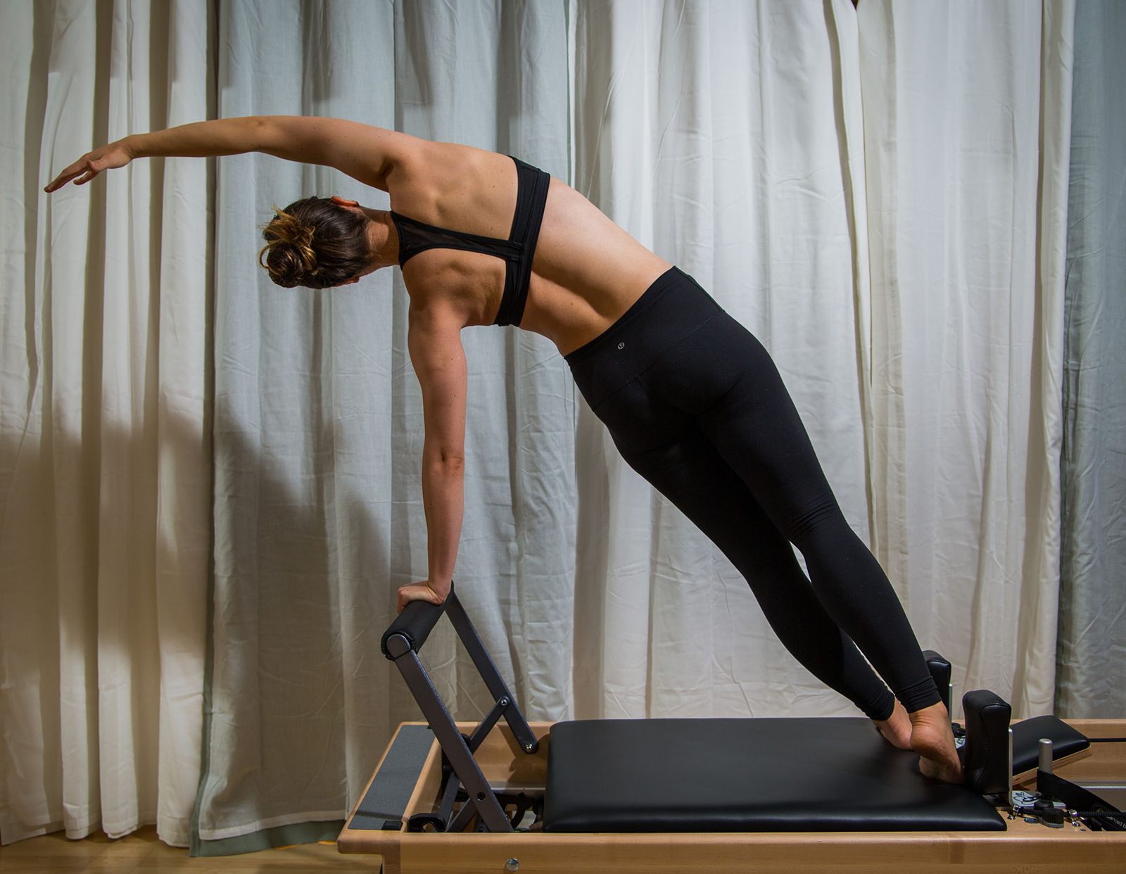 Kelly demonstrating a side plank on the Pilates reformer in the Fit Monkeys studio.